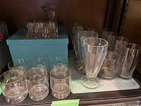 Overview of all glasses with Birks box on shelf, showing assortment of glassware sizes and styles.