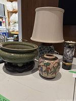 Front view showing lamp, crackle-glaze vase, celadon bowl on stand and black decorative vase