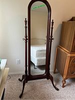Full view of the vintage freestanding mirror showing the wooden frame and base on carpet flooring.