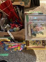 Top view photo showing boxes containing colorful embroidery threads, knitting needles, and packaged crafting items including tissue papers and butterfly decorations.