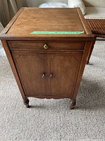 Front view of small wooden cabinet table with drawer and double-door storage compartment.