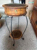 Full view of the round small folding table with wooden top and black rod iron legs