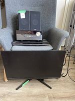 Sony stereo receiver, two Sony bookshelf speakers on a gray chair, Sony DVD player, and a 28-inch Samsung monitor in front.