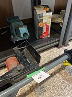 Blue work bench vice and red hydraulic bottle jack with box on shelf