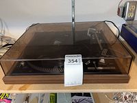 Front view of Dual 621 turntable with closed smoke-tinted dust cover on woodgrain plinth