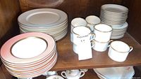 Shelved Fritz and Floyd Renaissance and Palais dinnerware set with stacked plates and cups.