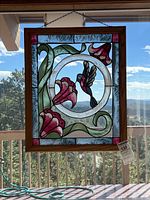 Full view of stained glass panel hanging in window, showing entire wood frame and design