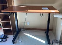 Full front view of the Jarvis electric height adjustable desk showing wooden top and control panel on black metal legs.