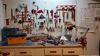 Front view of work bench and peg board with tools hung and laid out on the bench