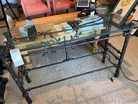 Full view of rectangular iron rod glass sofa table showing decorative leafy branch design on frame and clear glass top.