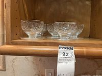 Group of eight Waterford crystal dessert cups on wooden shelf, showcasing design and size.
