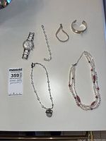 All items displayed: watch, cuff bracelet, two pearl necklaces, small beaded bracelets