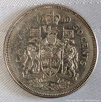 Close-up photo of the 1960 Canadian 50 cent coin, showing the coat of arms and date.
