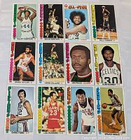 Image showing 12 vintage 1976-1977 NBA basketball cards arranged in three rows of four. Cards feature several NBA players with team names and colored borders.