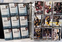 Reverse sides of hockey cards in plastic sleeve showing player stats and signatures