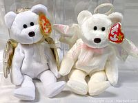 Two Angel Beanie Baby bears side by side in protective display cases.