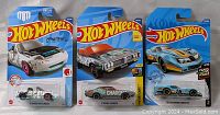 Three unopened Hot Wheels die-cast cars in original packaging including Mazda MX-5 Miata, Dodge Charger, and blue race car.