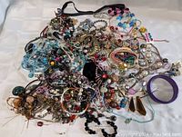 Photo showing a large assortment of various jewelry items such as bracelets, necklaces, earrings, and charms piled together showing diversity in style and color.