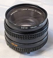 Front and side view of the Minolta MD Rokkor-X 50mm f/1.7 camera lens showing lens markings and serial number.
