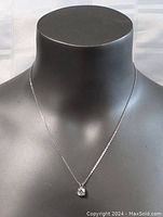 Photo of the necklace on a black bust showing the pendant hanging centrally.