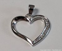 Close-up of the sterling silver heart pendant showing polished surface and stone detailing on one side.