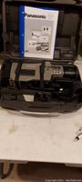 Photo showing the Panasonic AG-455P VHS camcorder inside its carrying case with the manual placed above.