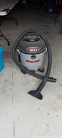 Full view photo of a Shop-Vac 10.5 gallon wet/dry vacuum with hose and nozzle attached, positioned on a concrete floor indoors.