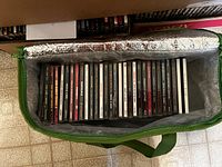 Green zippered bag with 30 distinct CD jewel cases, neatly organized in rows.
