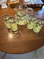 Full set of one pitcher and four glasses on wooden table, showing colorful design and clear acrylic material