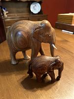 Photo showing the wooden mother elephant and baby elephant figures on a wooden surface, highlighting wood grain and figure size.