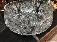 Close side view showing clear crystal bowl with intricate cut starburst and fan patterns and saw tooth edge