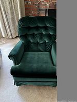 Front view of green velvet swivel rocker chair showing button-tufted backrest and cushioned seat.