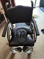 Side view of black wheelchair showing padded seat with removable center commode section and metal frame