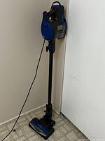 Full view of upright Shark Rocket vacuum cleaner showing blue and black design, corded with handle and clear dirt container.