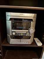 Sony AM/FM dual cassette stereo system with digital display, buttons, dials, and dual cassette decks visible, with remote control on shelf next to it.