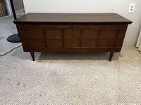 Front view of the Honderich cedar chest showing the paneled front and tapered legs in a dark wood finish.