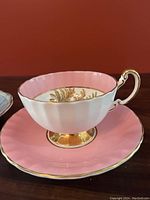 Close-up photo of the Aynsley pink teacup and saucer showing pink glaze inside, gold trimmed base, and gold leaf internal design