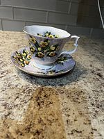 Side view of the teacup and saucer on a countertop showing the detailed floral pattern and gold trim