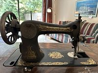 Close-up of the black Singer sewing machine showing gold decorative decals and the brand name.