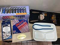 Overview of acrylic paint tubes, graphite set, pastel boxes, brushes and paint tray