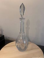 Full view of the 16-inch tall clear crystal wine decanter with stopper on a wooden surface.