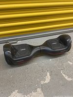 Front view of the black hoverboard with red accents and textured footpads labeled 'Torogo' and 'Hoverboard.'