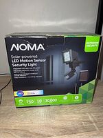Box of NOMA Solar-Powered LED Motion Sensor Security Light showing product name, features, and specifications.