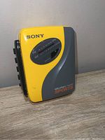 Front view showing Sony branding, AR/FM radio tuner, yellow and gray body, and Sports Walkman label.