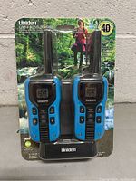 Front view of the Uniden GMR 4055-2CKHS 2-way radios in original sealed packaging displaying two radios and charging dock.