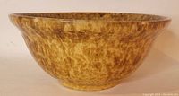 Side view showing the brown-yellow mottled glaze and flared shape of the antique Bennington bowl.