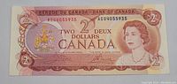 Front side of the Canadian two dollar bill showing Queen Elizabeth II and detailed engraving in red tones.