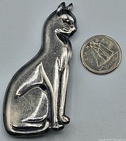 Front view of the large sterling silver cat brooch next to a Canadian dime for scale, showing the cat's elegant sitting pose and polished surface.