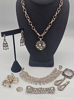 Full group photo showing chain necklace with pendant, two bracelets, earrings, brooches, and buckle.