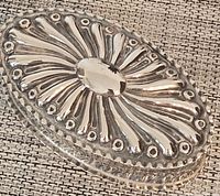 Top angled view of silver oval trinket box with embossed sunray pattern on lid